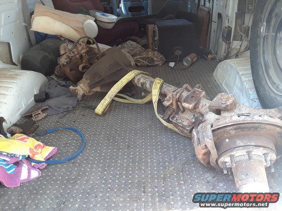 Axle assembly with yellow strap, blankets, and a speaker in a cargo area