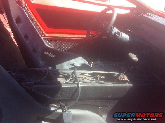 Interior of a red vehicle, showing racing seats, steering wheel, and center console with wiring