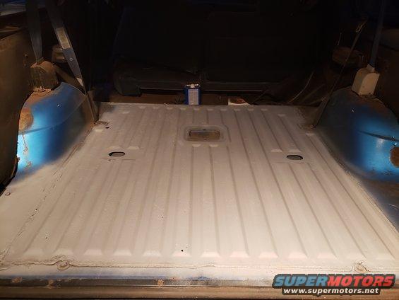 Interior cargo area of a vehicle, showing the floor with ribbed texture and blue painted wheel wells