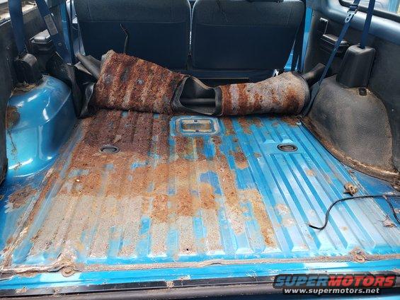 blue vehicle cargo area with rusty floor and a removed exhaust pipe