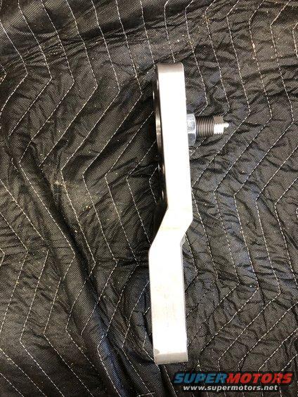 Metal automotive part with a threaded bolt and spring, viewed from the side against a quilted black background