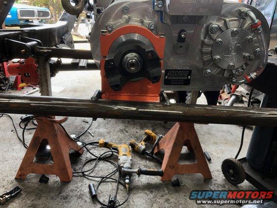 Transfer case mounted on orange bracket, supported by jack stands
