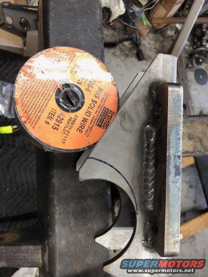 Spool of MIG solid wire next to a metal bracket with welds