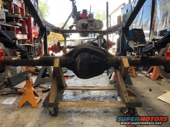 Jeep Wrangler frame and suspension parts on jack stands, with engine overhead