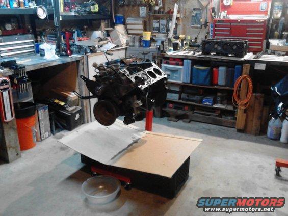 engine on a stand in a garage, with tools and shelves in background