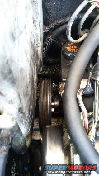 Close-up of engine pulley and power steering fluid reservoir with cap reading 'POWER STEERING FLUID ONLY'