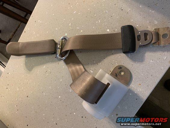 Tan seat belt assembly with metal buckle and plastic retractor mechanism