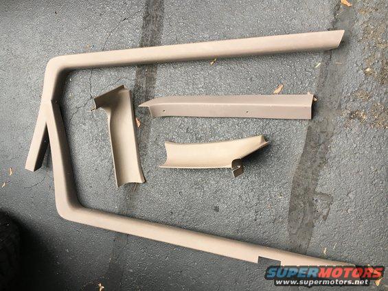 Tan interior trim pieces laid out on asphalt