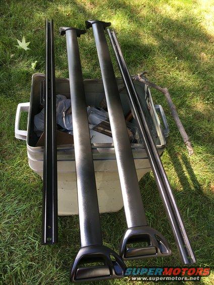 Roof rack crossbars and side rails in a plastic bin on grass