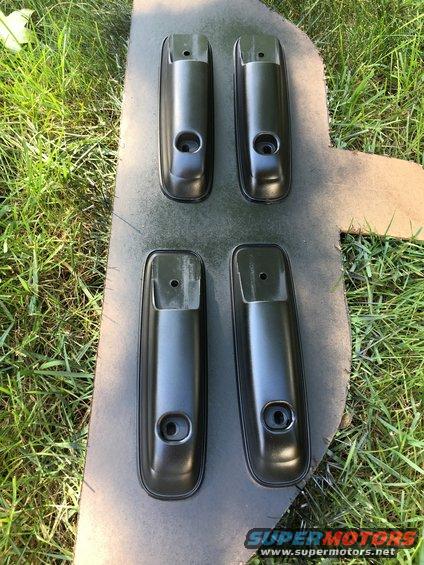 Four black door handles on a spray-painted surface