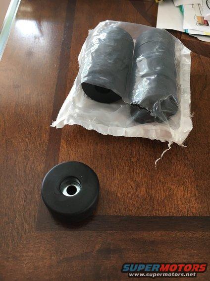 Two rubber bump stops in plastic packaging and one loose bump stop on a wooden table
