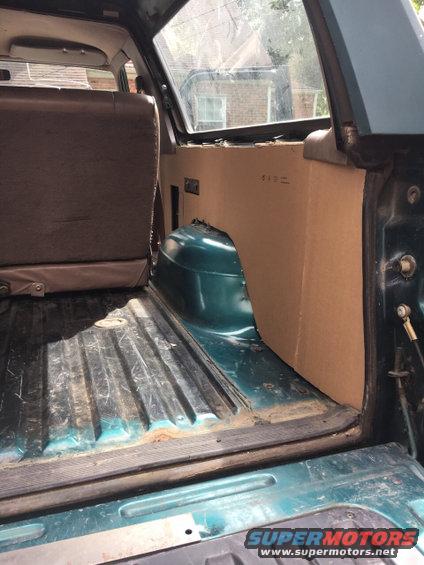 Green SUV interior cargo area with brown seats and cardboard paneling. Visible rust on the floor