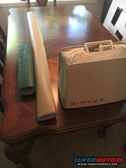 Singer sewing machine case and two rolled tubes on a wooden table