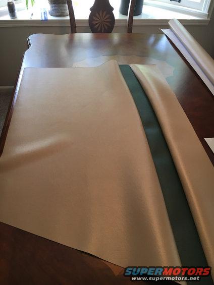 tan and green material laid out on a wooden table, with a roll of material in the background