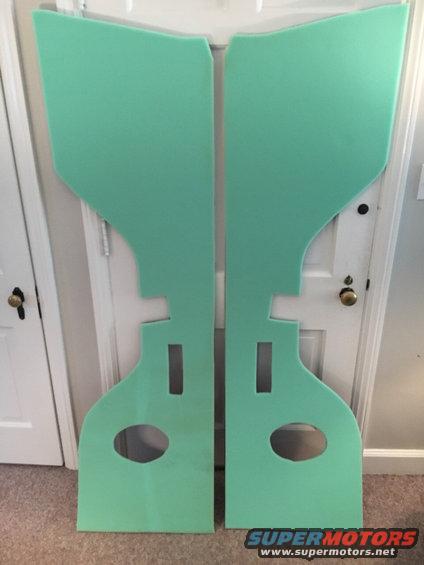 Two green door panels with cutouts for speakers and door handles, leaning against a closed door