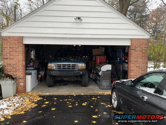 1996 Ford Bronco parked in an open garage with a black car to the right