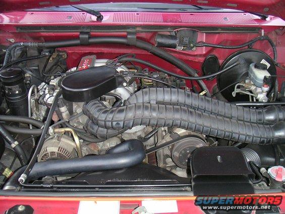 Red vehicle engine bay with large black air intake hoses
