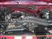 1994 Ford Bronco - The engine bay of a red vehicle, prominent black air intake hoses and various engine components.