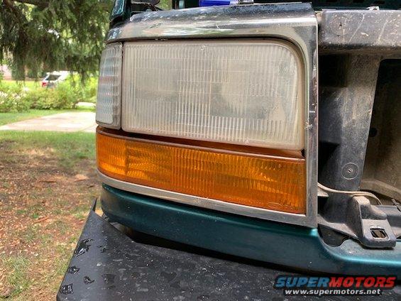 Green Ford Bronco front corner with a clear headlight and amber turn signal. The grille area is visible