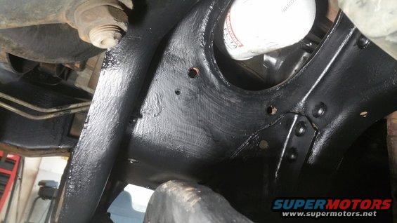 Close-up of black painted vehicle front suspension components and an oil filter