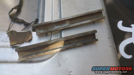 Two metal channels with debris and wiring on a textured surface