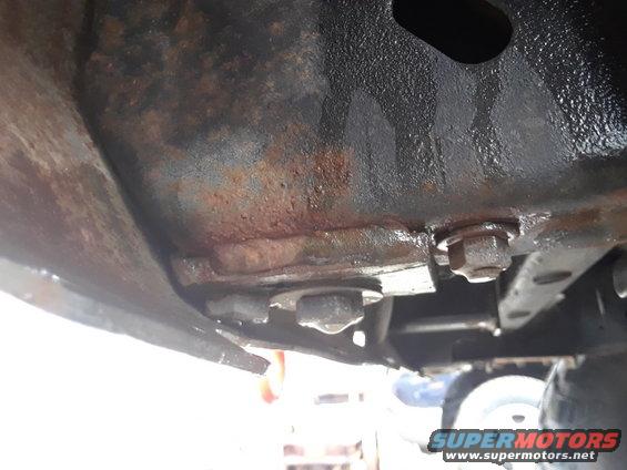 Close-up of rusty vehicle frame with bolts and undercarriage components