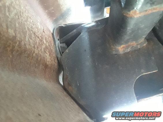 Close-up of a rusty vehicle frame rail and a black metal hitch bracket
