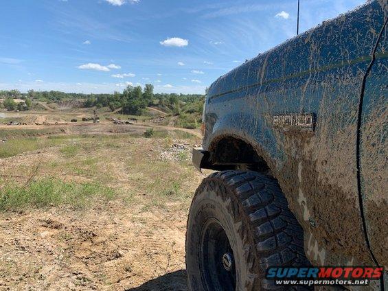 Mud-covered 1996 Ford Bronco, right front quarter panel and tire visible, off-road terrain