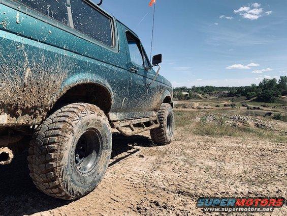 Mud-splattered 1996 Ford Bronco parked on an off-road course with a bright orange flag on top