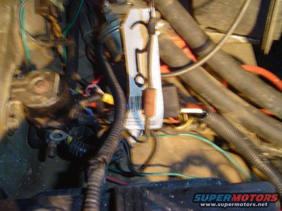 Close-up of tangled engine bay wiring with a white tag and barcode