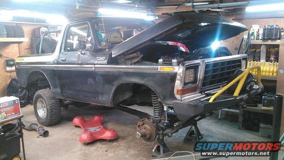 1978 Ford Bronco with hood open, on jack stands, front end disassembled in a garage