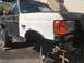 1989 Ford Bronco - Front fender and headlight assembly of a Ford F-Series truck, showing a white fender and black hood.