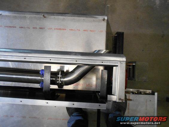 Close-up of a custom exhaust pipe with clamps and blue fittings, mounted on a metal frame