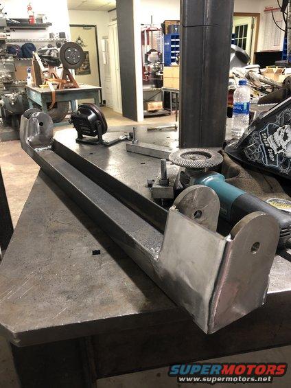 Welded steel fabrication part on workbench with grinder and welding mask