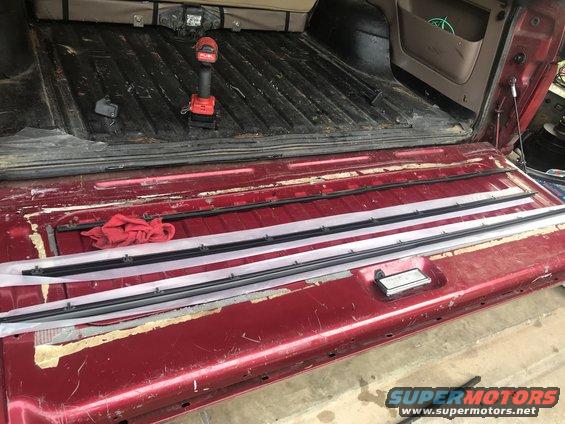Red Ford Bronco tailgate with new weather stripping laid out and a red drill on the bed floor