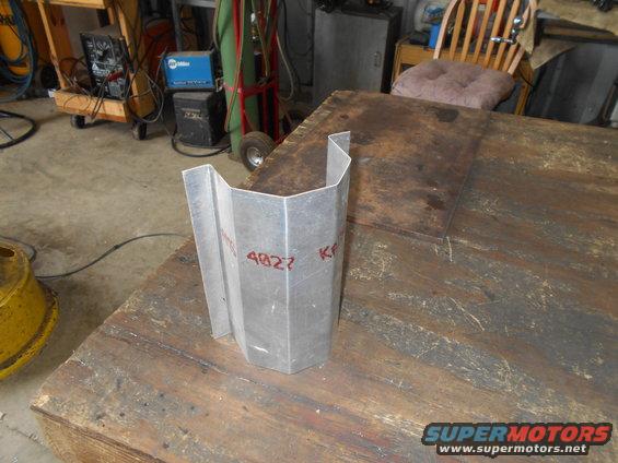 Metal bracket with red markings '4827' and 'KF' sits on a workbench