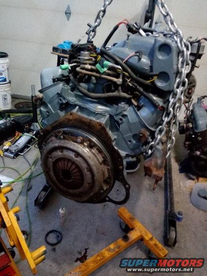 Engine with clutch assembly hanging from chains, supported by an engine hoist