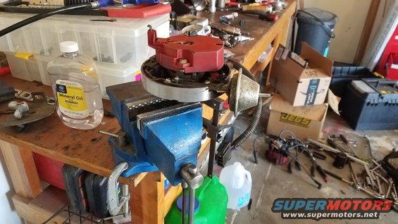 Distributor held in a vise on a workbench with mineral oil and tools