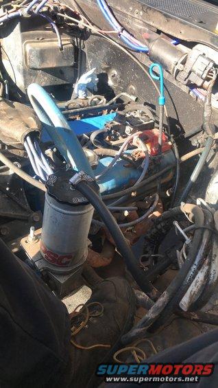 Engine bay with blue valve covers and a silver canister with red lettering