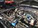 1989 Ford Bronco - The engine bay of a vehicle is shown with various tools and parts. Another truck is parked nearby.
