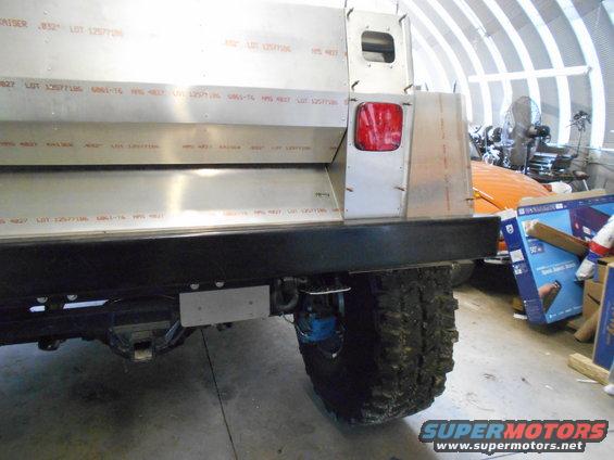 Custom vehicle rear with aluminum panels, red taillight, and large tire