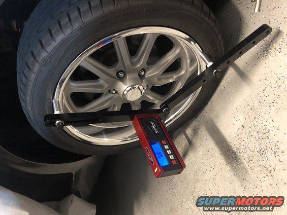 Close-up of a digital wheel alignment tool attached to a car's wheel and tire