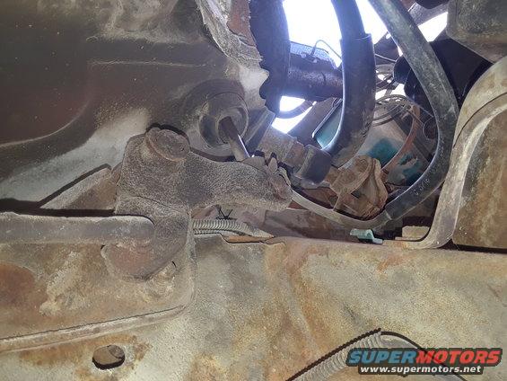 Undercarriage of a rusty vehicle showing suspension parts and hoses