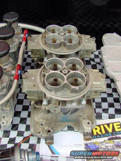 Dual carburetors with braided fuel lines on a checkered background