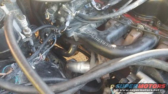Close-up of an engine bay showing an exhaust manifold with 'ORRENHAUSE' visible, along with various hoses and wiring