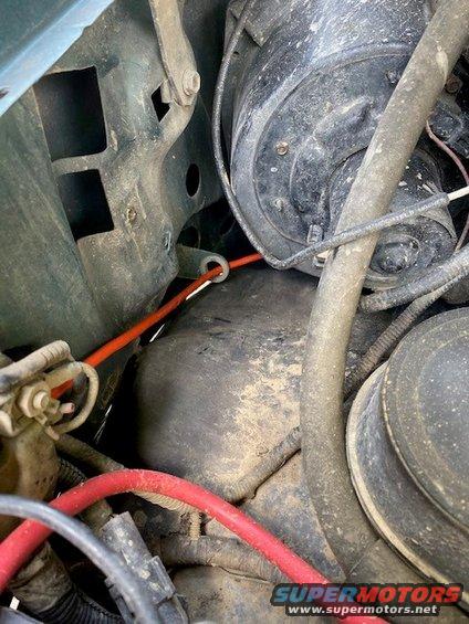 Engine bay with red wire routed through a grommet