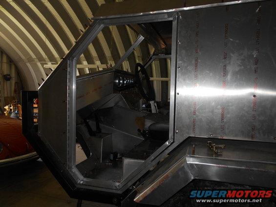 Unfinished vehicle interior with metal paneling and steering wheel
