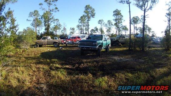 Green 1996 Ford Bronco parked in mud with other trucks and an RV in background