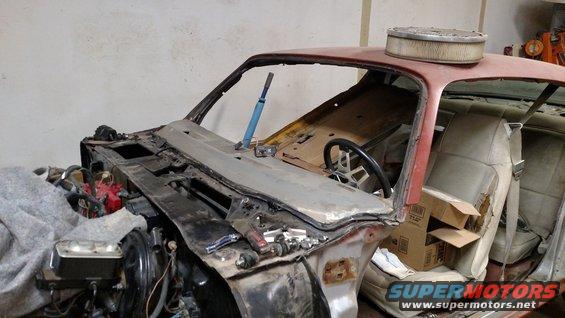 Red car interior with disassembled dashboard, steering wheel, and engine components visible