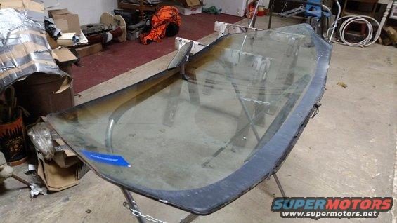 windshield on a stand in a garage, with boxes and tools in the background